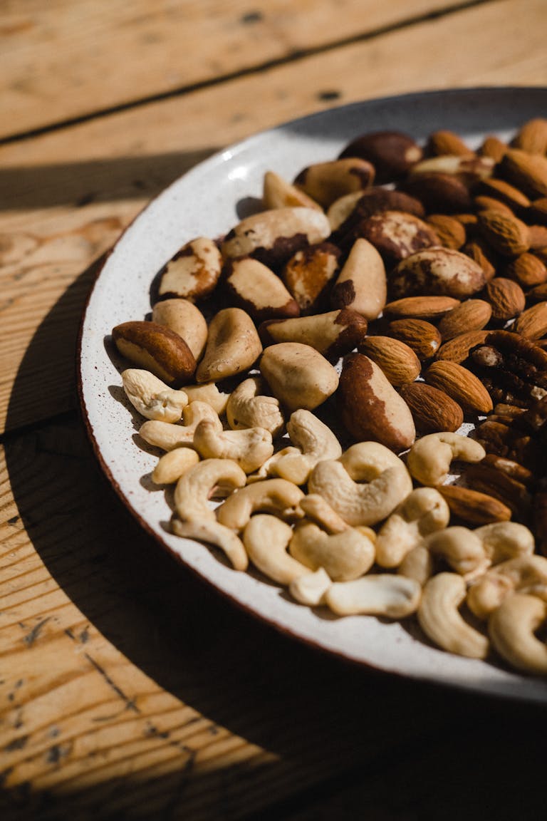 A close-up of various nuts on a ceramic plate, showcasing texture and natural light.