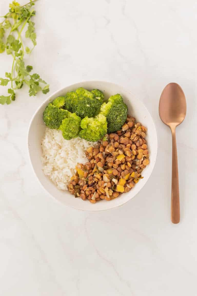 A minimalist vegan meal featuring rice, broccoli, and spiced lentils.