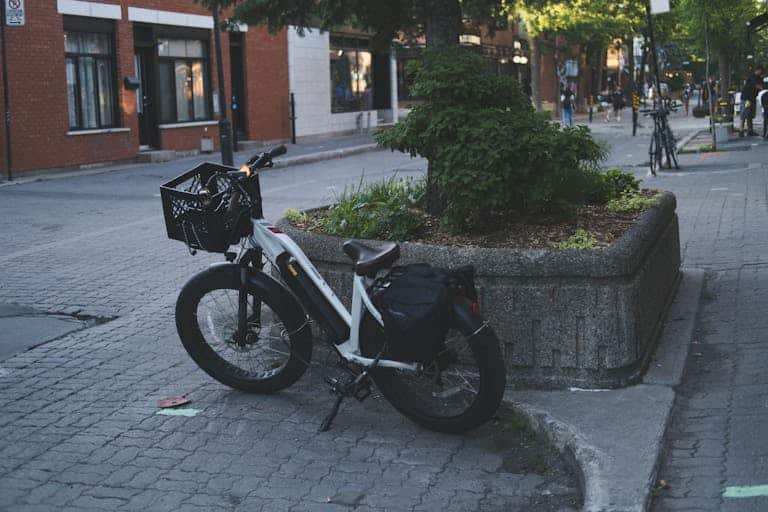 A parked bicycle on a quiet city street corner with greenery, showcasing urban lifestyle.