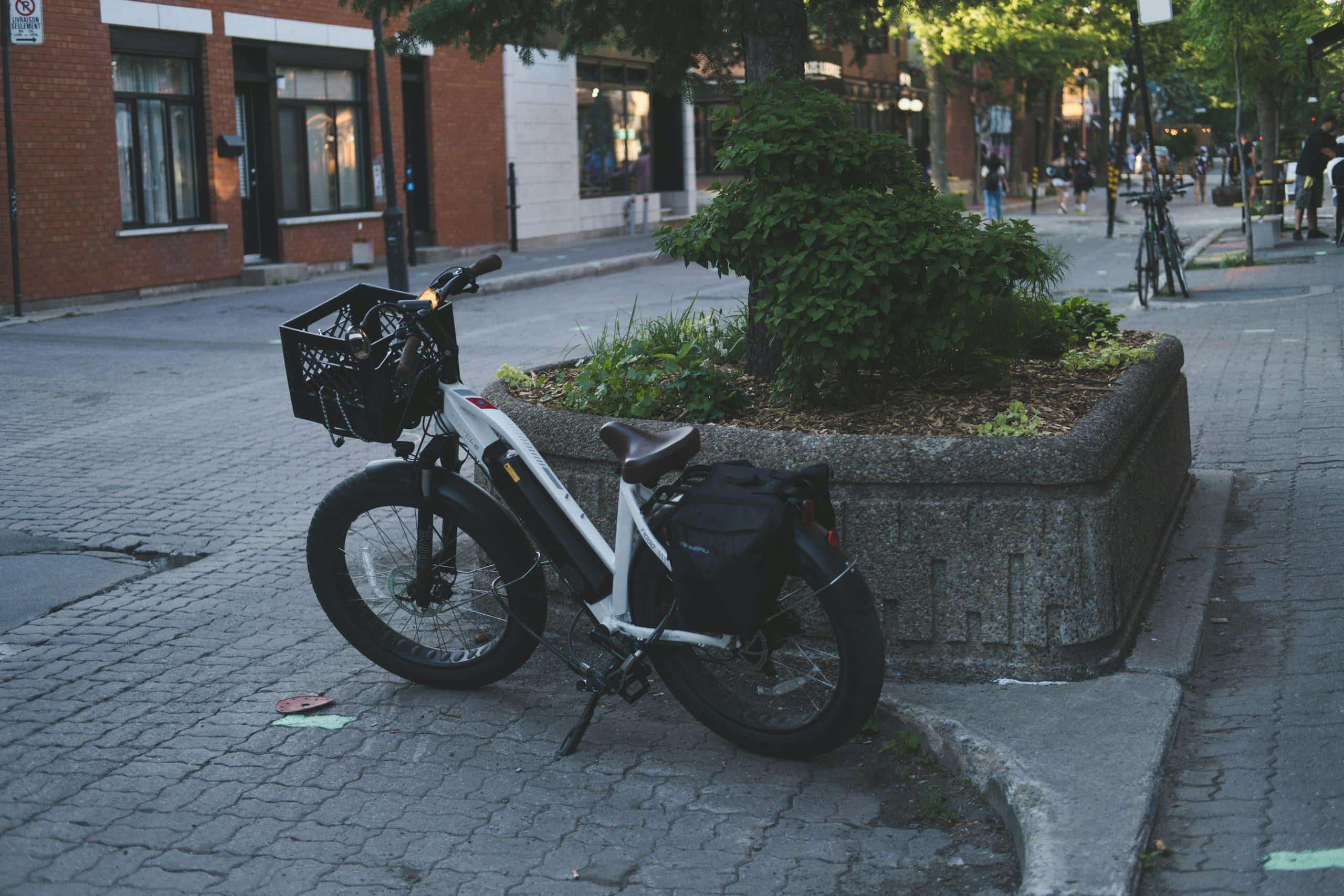 A parked bicycle on a quiet city street corner with greenery, showcasing urban lifestyle.