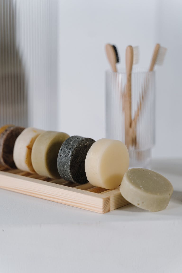 Close-up of eco-friendly solid soap bars and wooden toothbrushes on a minimalist bathroom counter.
