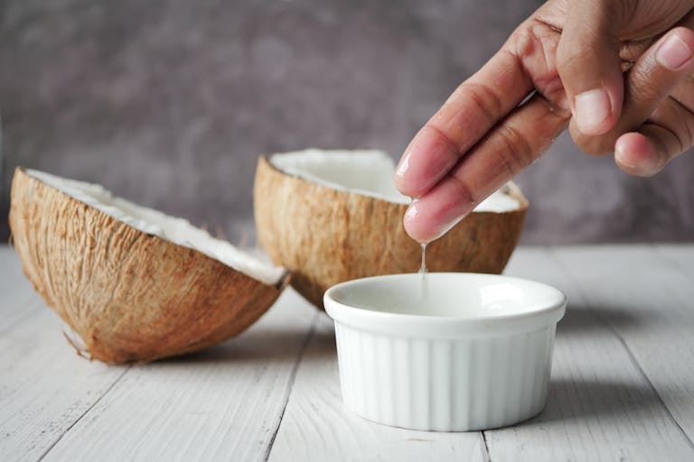 Hand extracting coconut oil into a bowl, ideal for natural skincare routines.