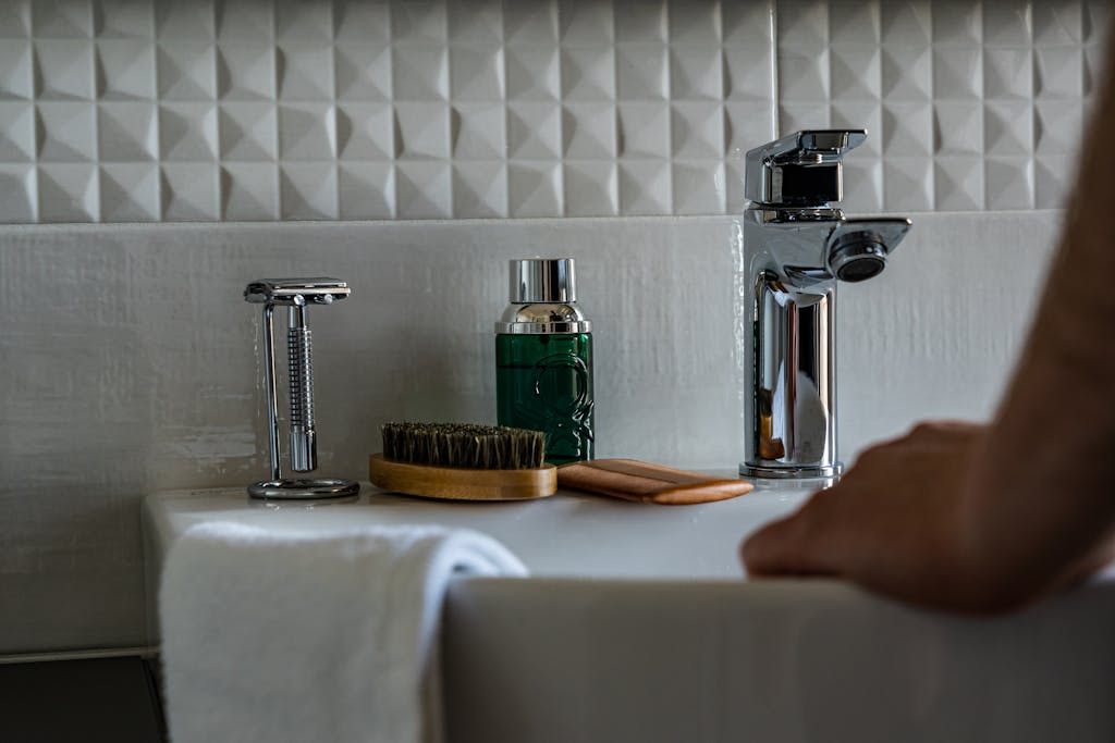 Close-up of bathroom sink with grooming tools, a faucet, and tiled backsplash.
