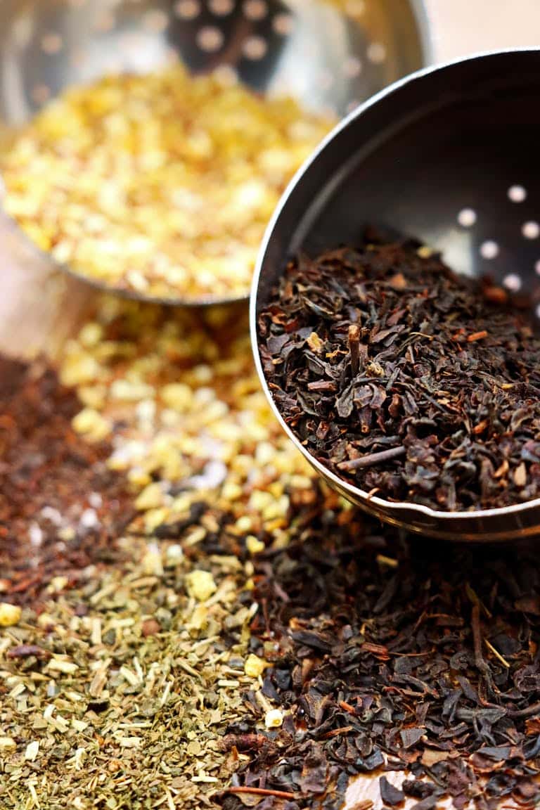 Close-up shot of assorted loose leaf teas and herbs in a stainless steel strainer.