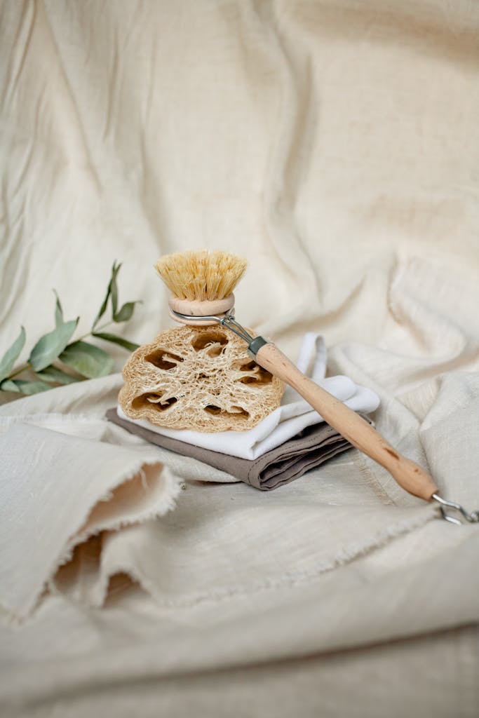 Sustainable cleaning brush on soft linen towels with leaf accents.