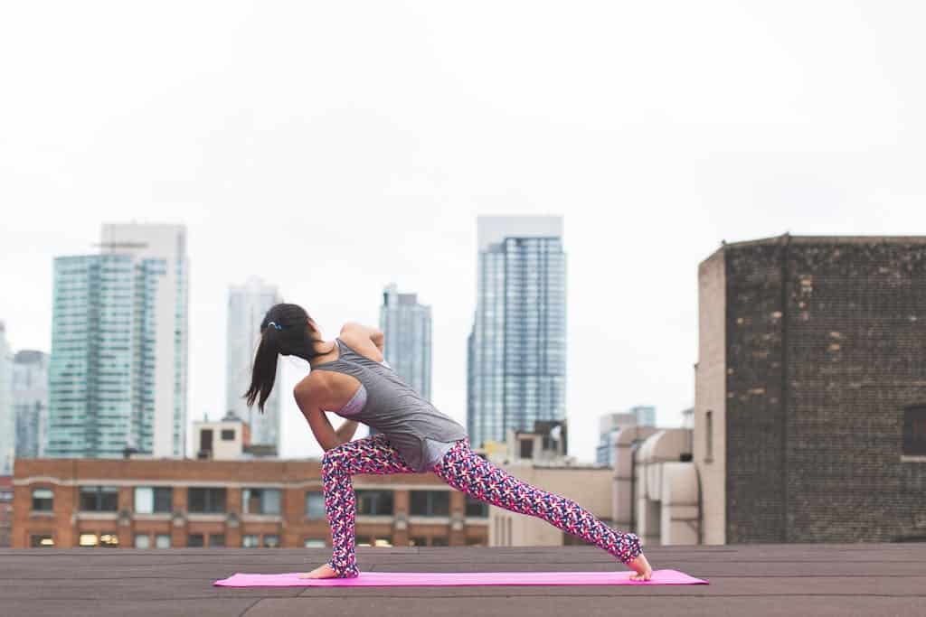Woman in yoga pose on city rooftop, capturing urban wellness.
